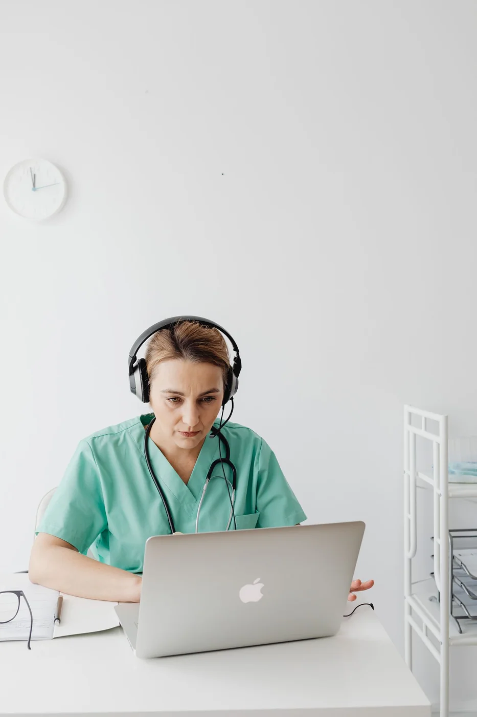 A doctor wearing a headset at a laptop for a video consultation